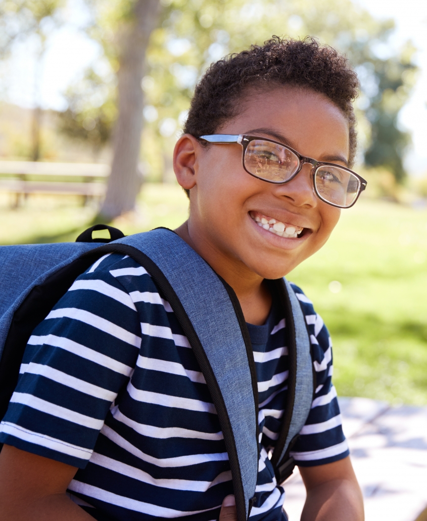 Young mixed race schoolboy in glasses smiling to camera