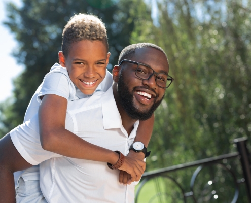 Delighted happy man carrying his son on the back
